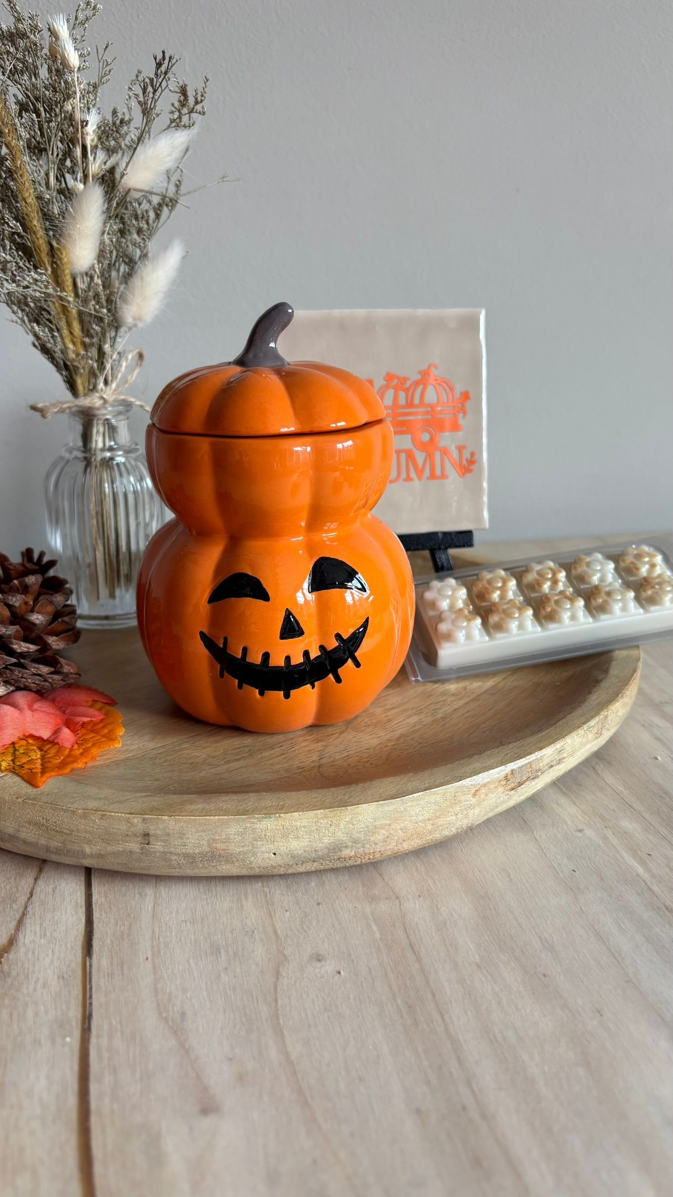 Halloween pompoenversiering op een houten dienblad met herfstdecoratie en kaarsen.