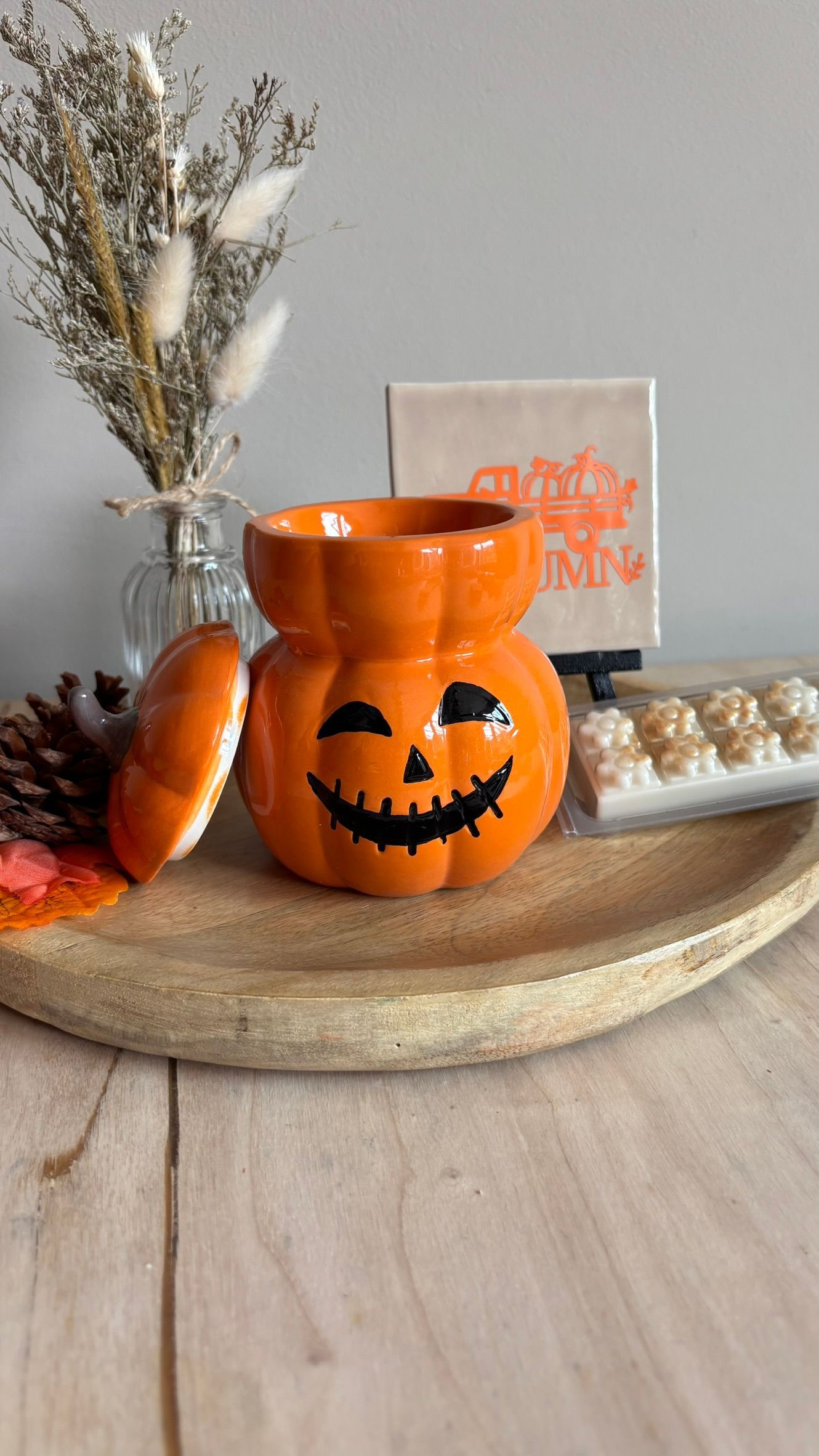 Halloween pompoenversiering op een houten dienblad met herfstdecoratie en kaarsen.
