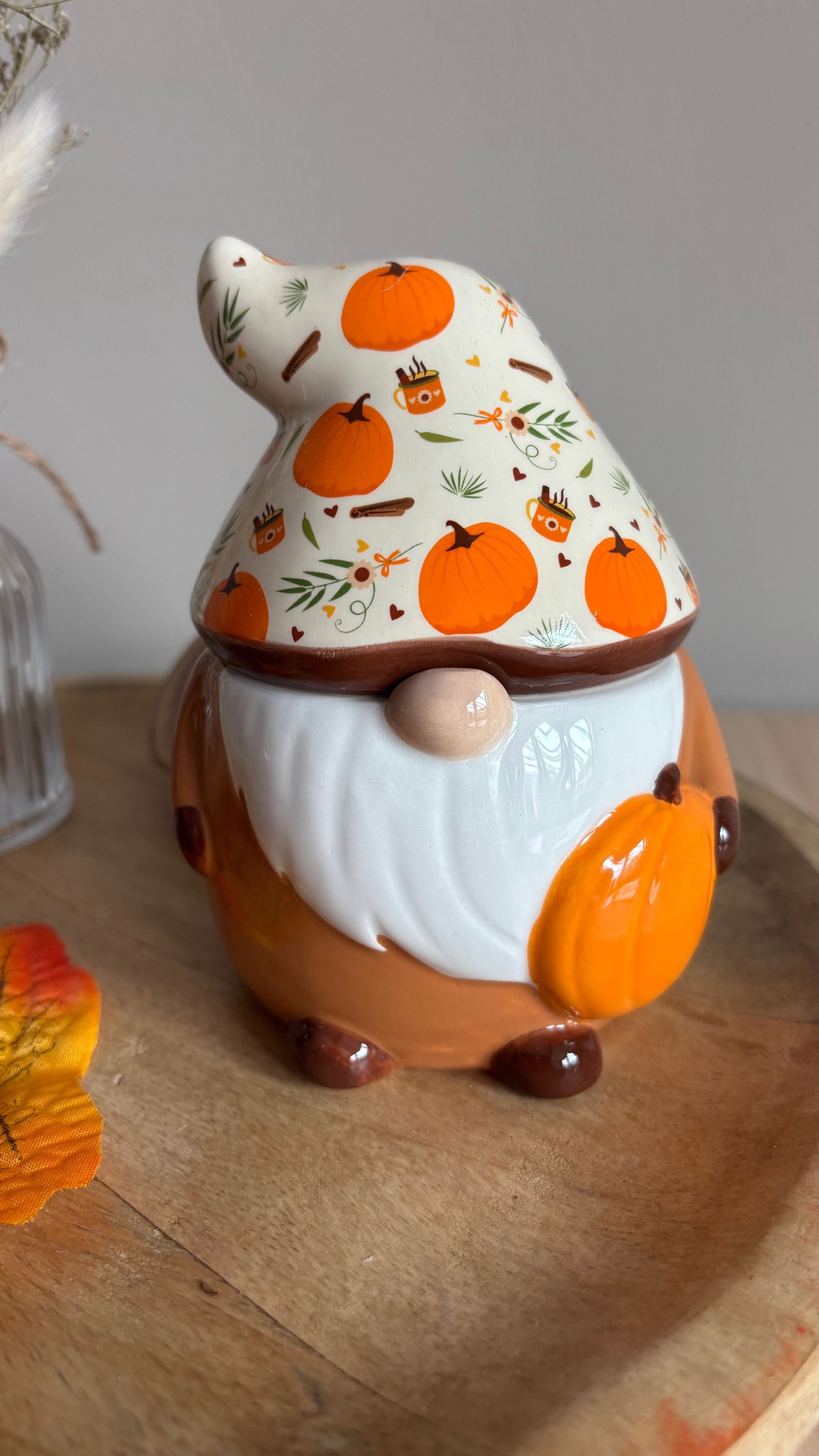 Klein keramisch muisje naast gedroogde bloemen en een dennenappel op een rond houten dienblad.