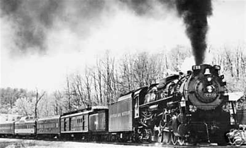 A black and white photo of a train with smoke coming out of it.
