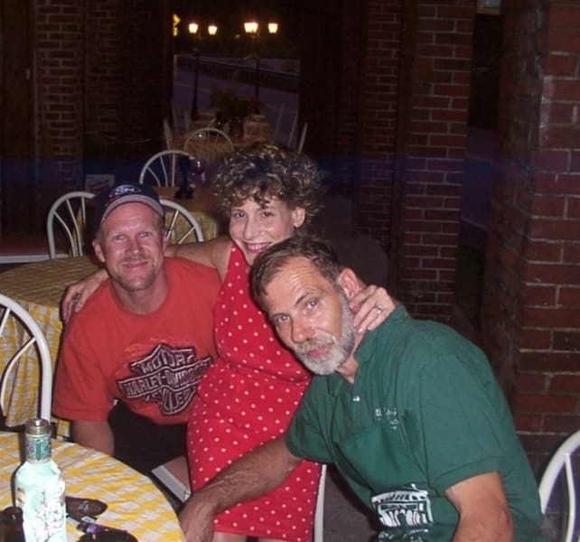 A man in a harley davidson shirt sits with two other men