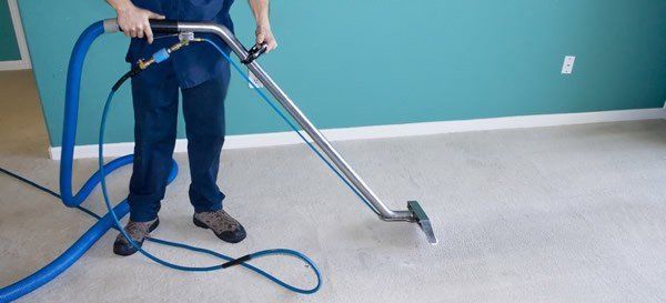 Cleaner wiping a cloth along grout lines between tiles to remove dirt and stains, revealing a cleaner and brighter surface.