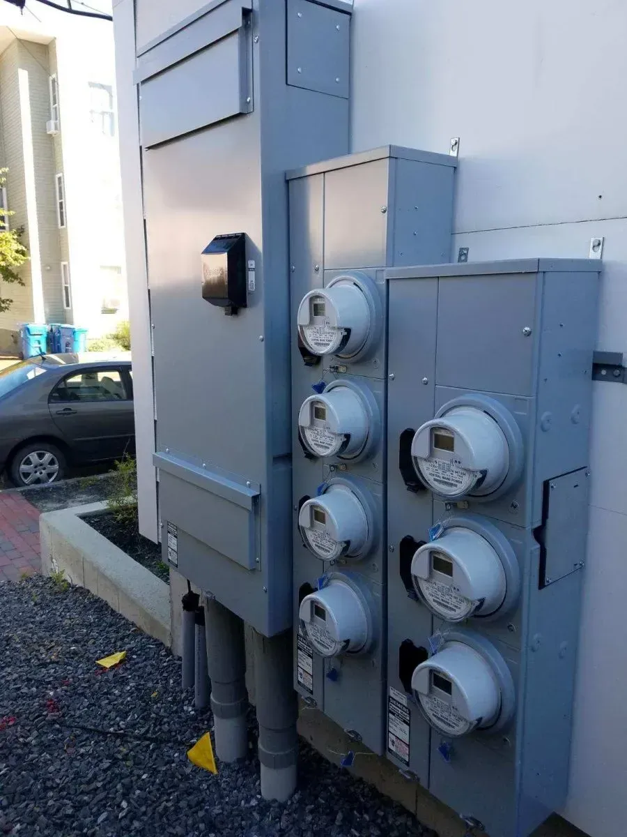 A row of electrical boxes with meters attached to them on the side of a building.
