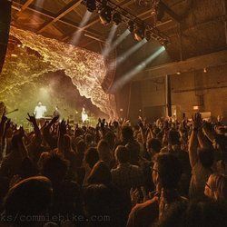 A crowd of people are standing in front of a stage at a concert.
