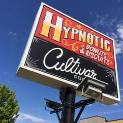 A large billboard sign for hypnotic donuts and biscuits.