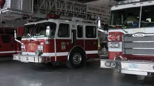 A fire truck is parked in a garage next to another fire truck.