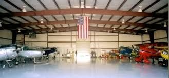 A hangar filled with planes and a flag hanging from the ceiling.