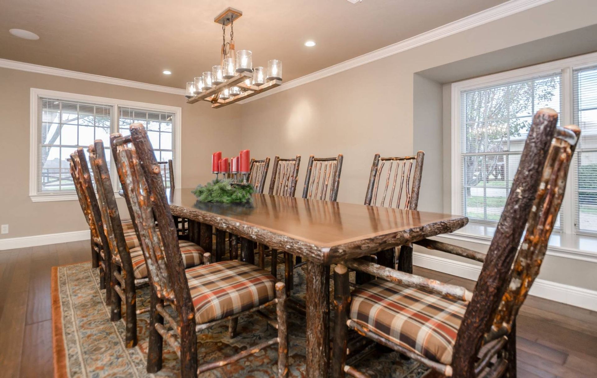 A dining room with a wooden table and chairs and a chandelier.