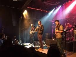 A group of men are playing instruments on a stage in a dark room.