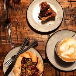 A wooden table topped with plates of food and a cup of coffee.