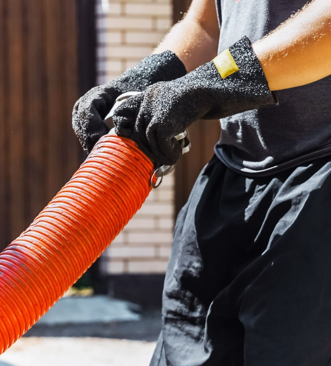 Person Wearing Protective Gloves Connecting an Orange Hose — All Class Liquid Waste in Millmerran, QLD