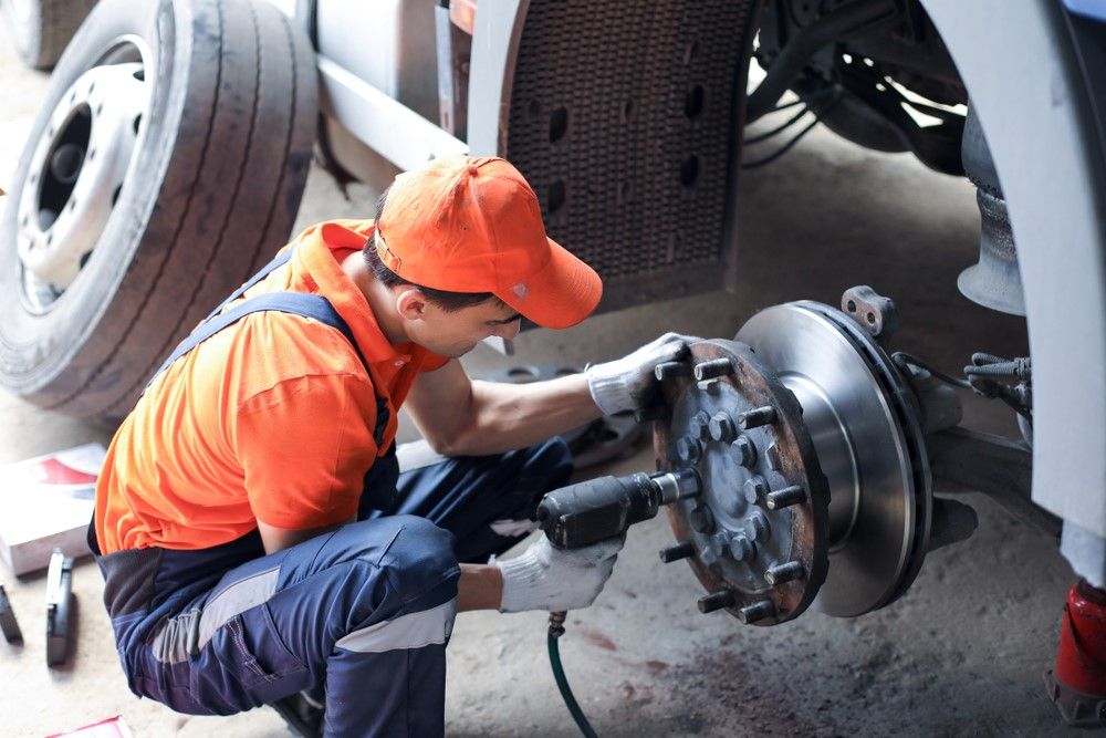 A Person is Fixing A Brake Pad Of A Truck — Cadillac Transport Repairs in Winnellie, NT