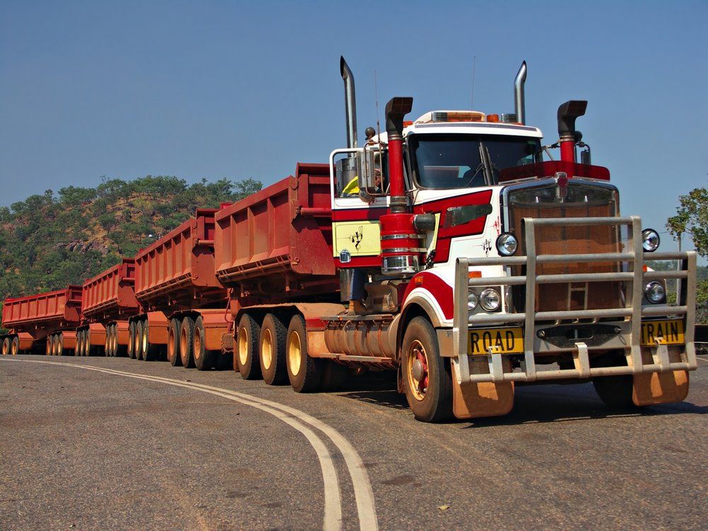 Red And White Road Train Truck Hauling Multiple Trailers On A Road — Cadillac Transport Repairs in Winnellie, NT