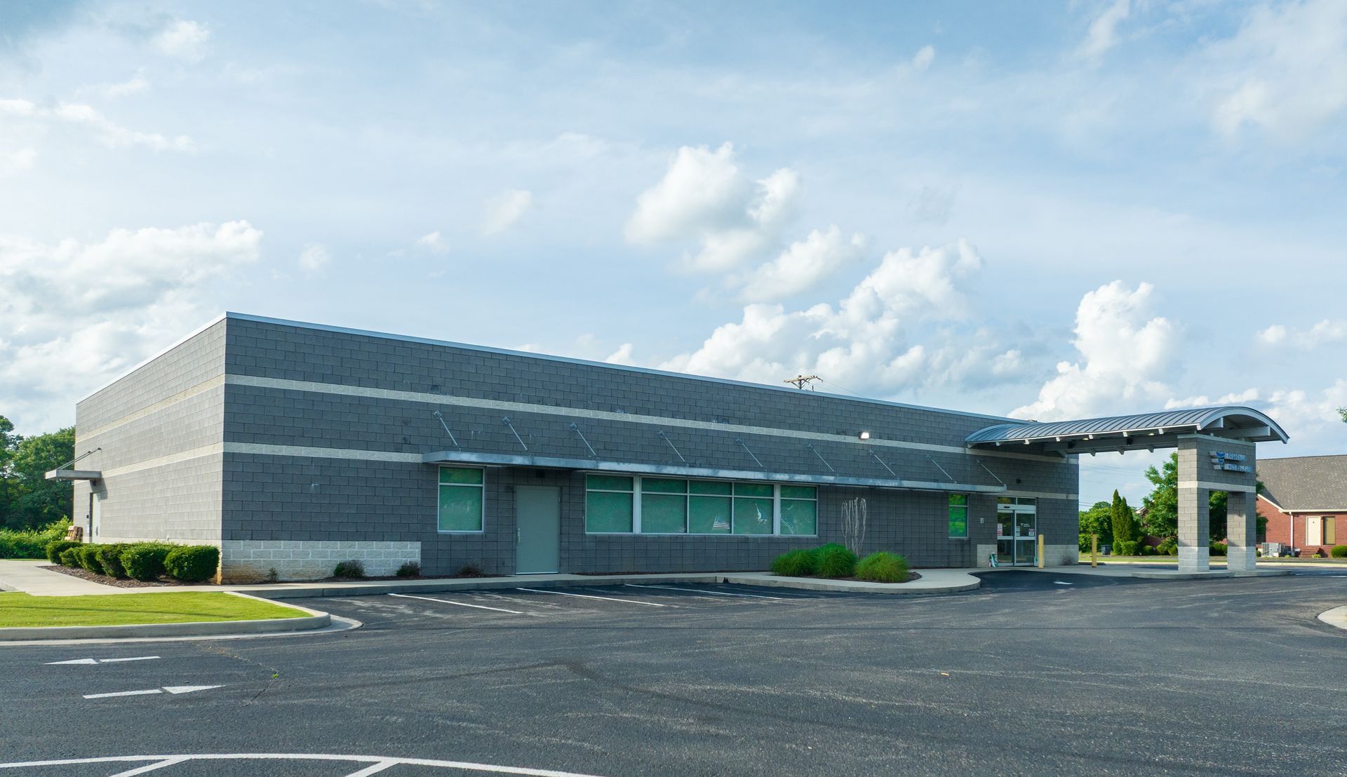 Modern low-rise Fresenius Medical Care commercial building with gray siding and teal windows beside an empty parking lot