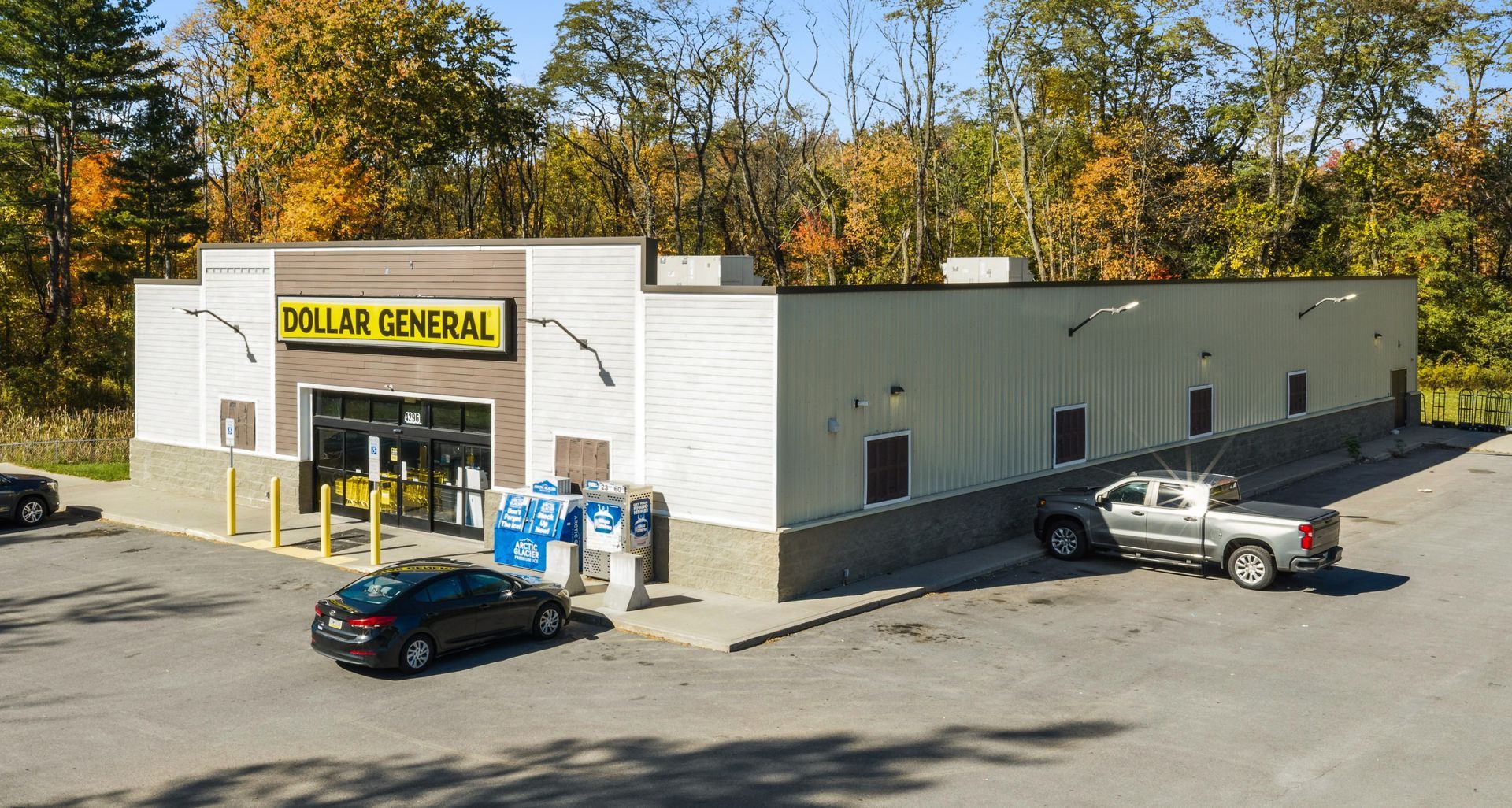 Dollar General storefront with parked cars and a delivery truck outside in a small parking lot.