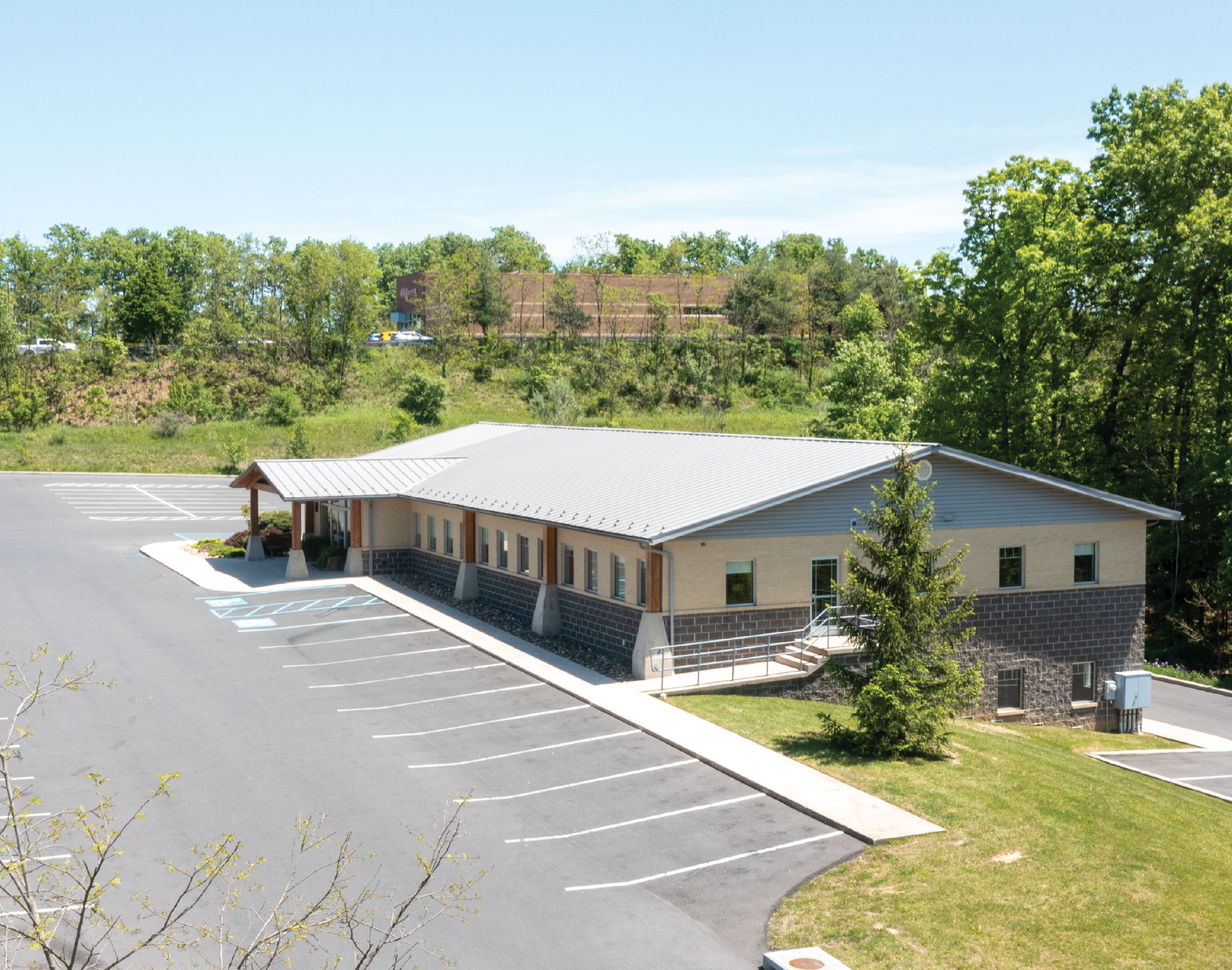 Single-story Heartland Dental building with stone trim and empty parking lot, surrounded by trees under a clear sky