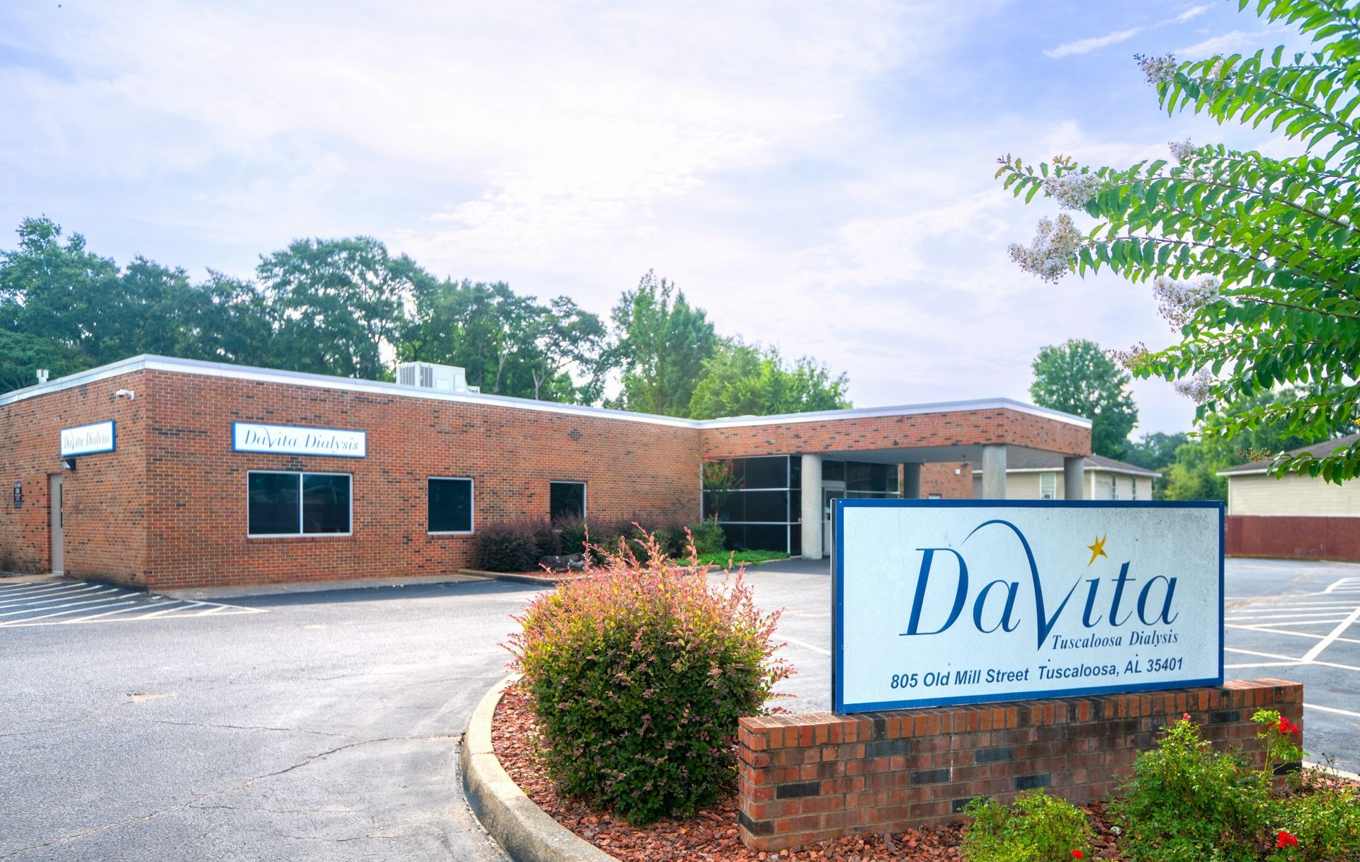 DaVita clinic exterior with brick building, parking lot, and landscaped entrance sign