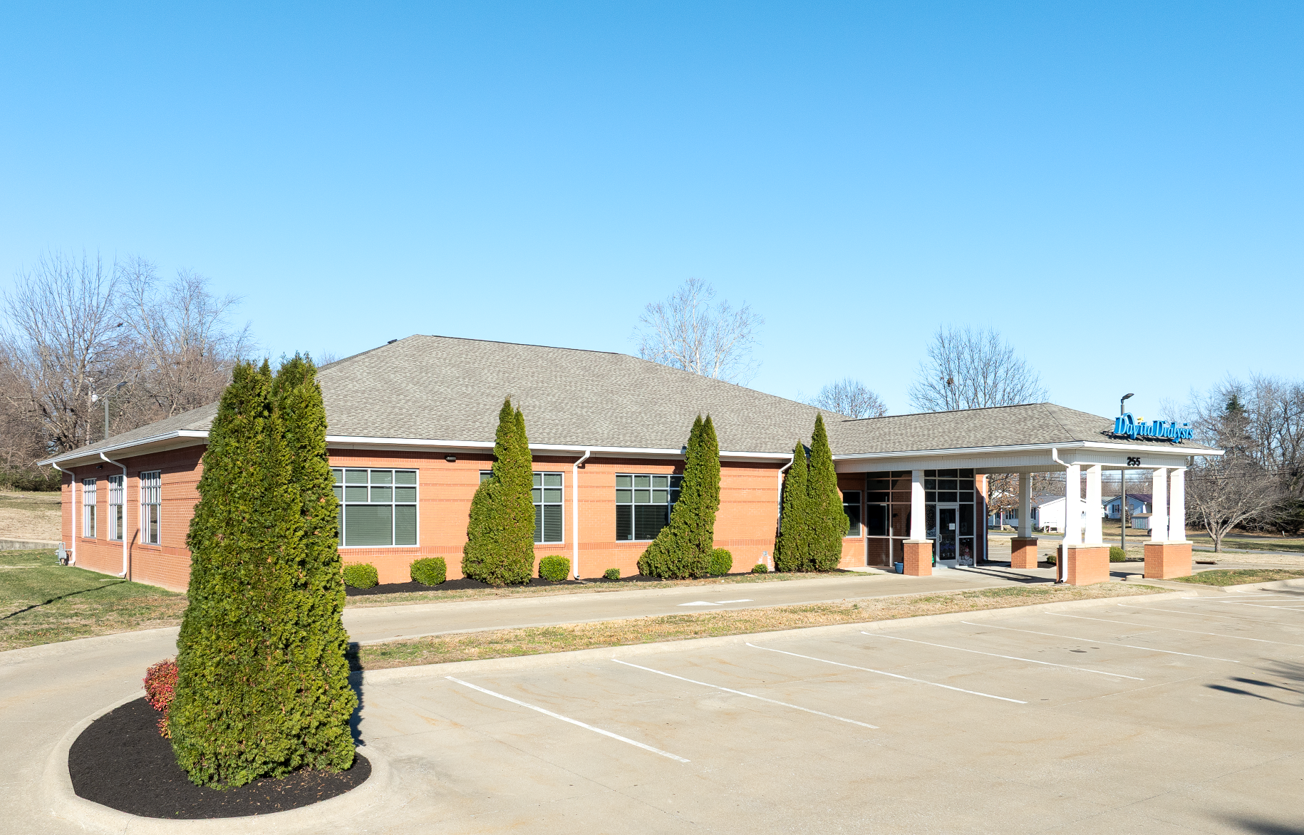 Net lease davita dialysis facility building with a brown roof and a small parking lot