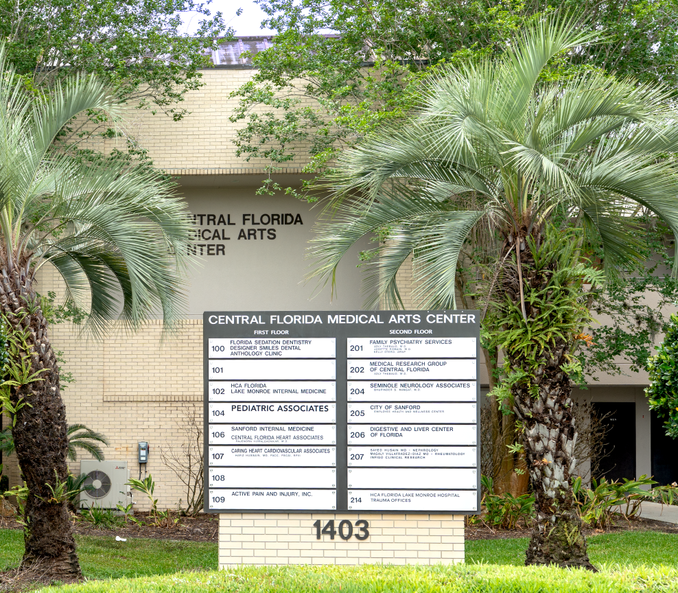 Central Florida Medical Arts Plaza sign with list of tenants including Pediatric Associates outside a beige building with palm trees and greenery, address number 1403