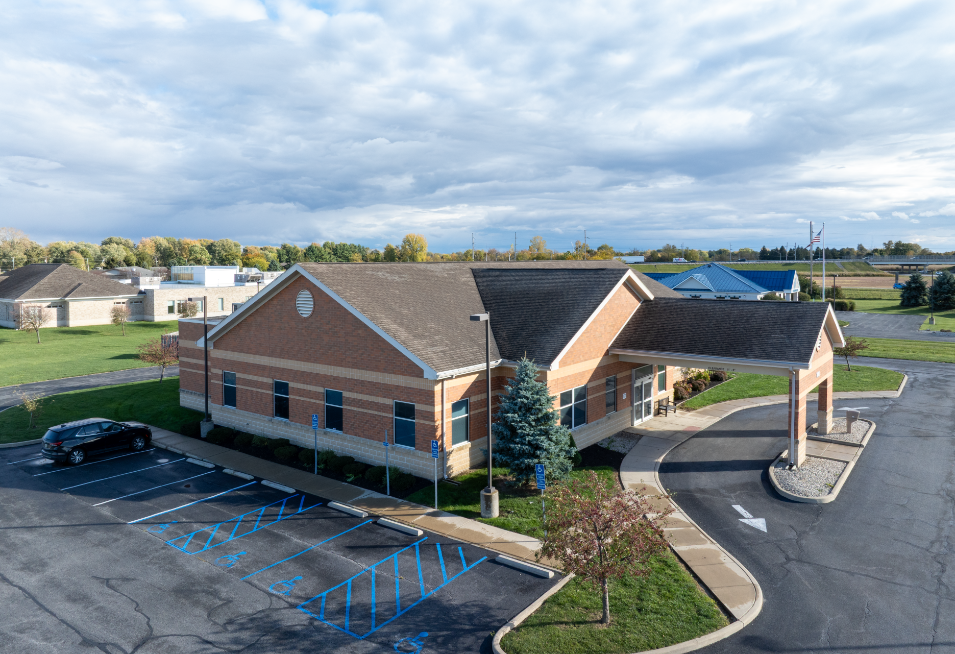 DaVita Dialysis kidney care building with brown roof and covered entrance, parked car, and blue sky.