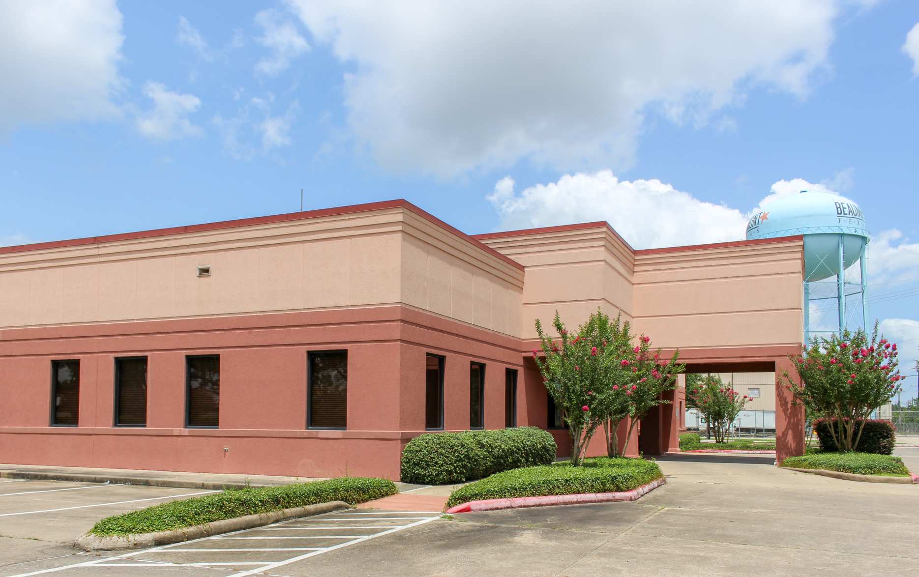 DaVita clinic brick building with red trim, windows, shrubs, and a Beaumont water tower in the background