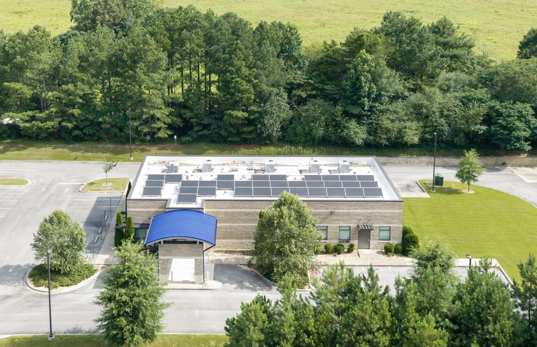 Aerial view of a fresenius medical care building with a blue awning, surrounded by trees and a parking area