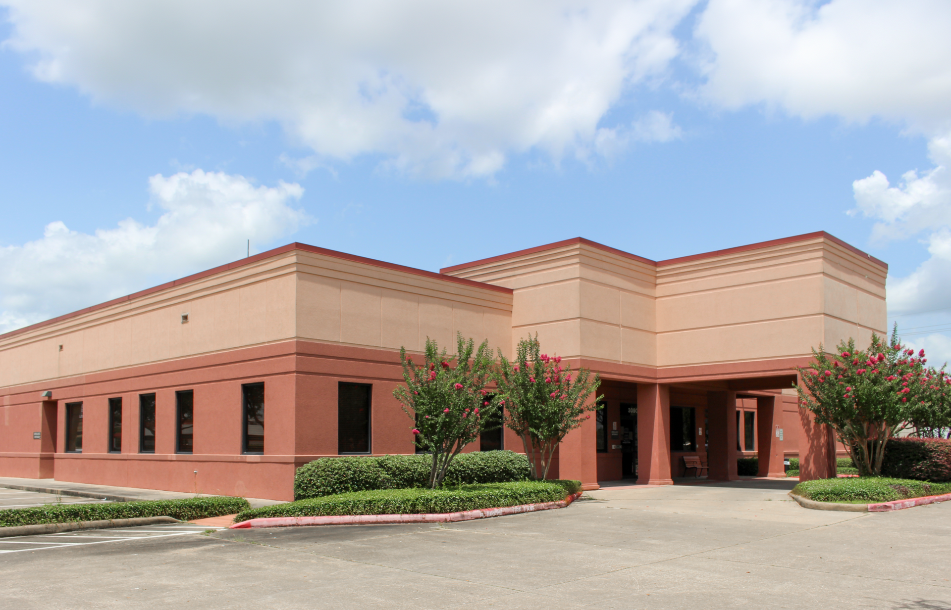 DaVita Dialysis beige commercial building with a covered entrance and landscaped shrubs under a blue sky