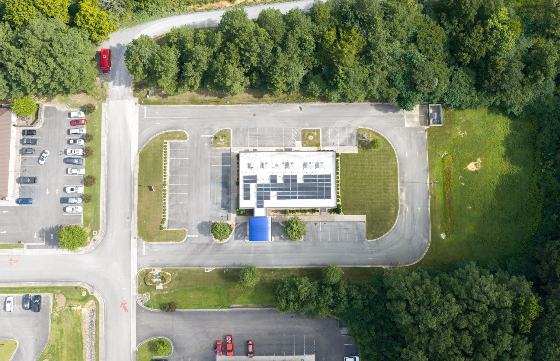 Aerial view of a single tenant medical building with parking lots, roads, and surrounding trees.