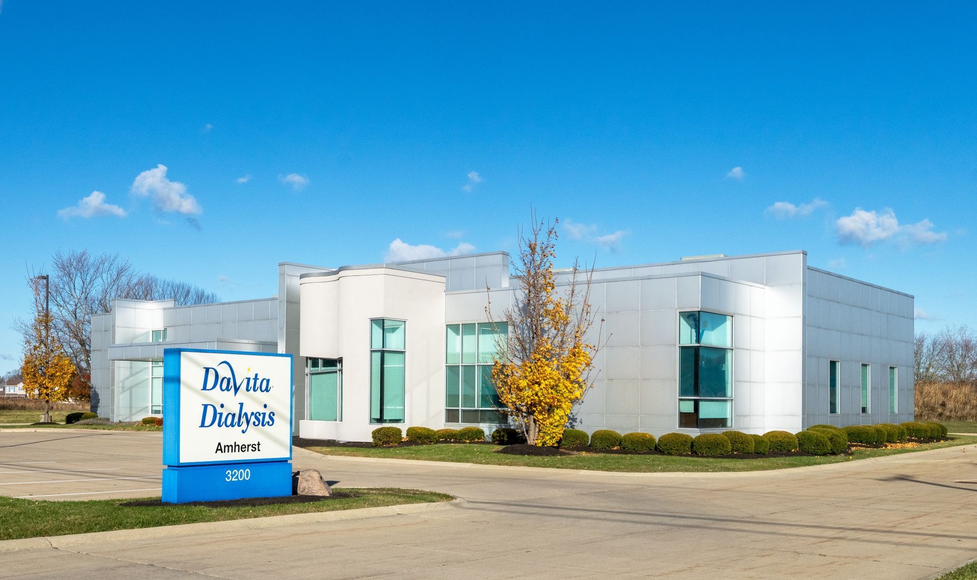 Modern white office building with a blue sign reading “DaVita Dialysis” under a clear sky.