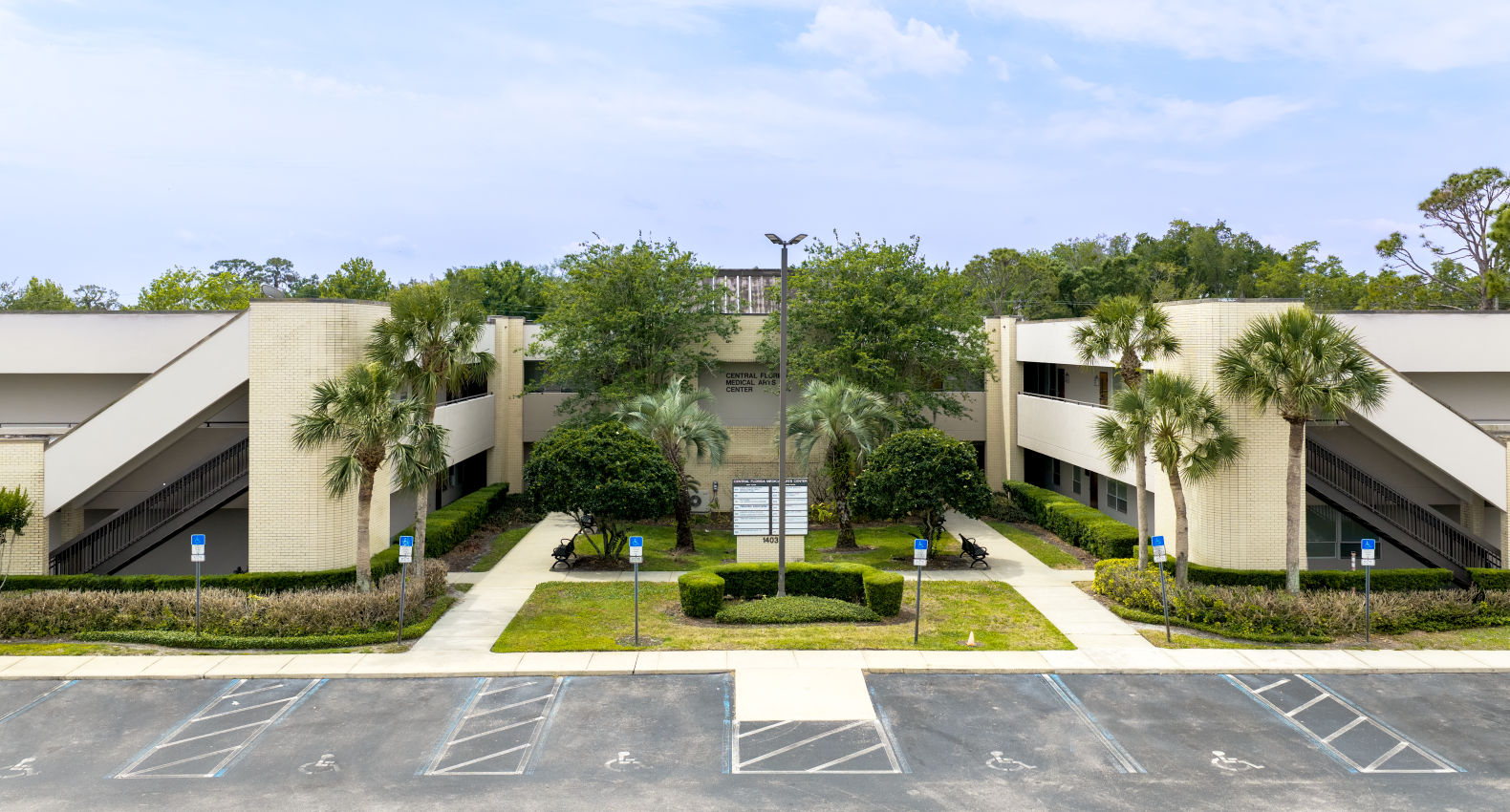 Elevated view of Pediatric Associates entrance into Central Florida Medical Arts Center with white walls, trees, and a parking lot in front