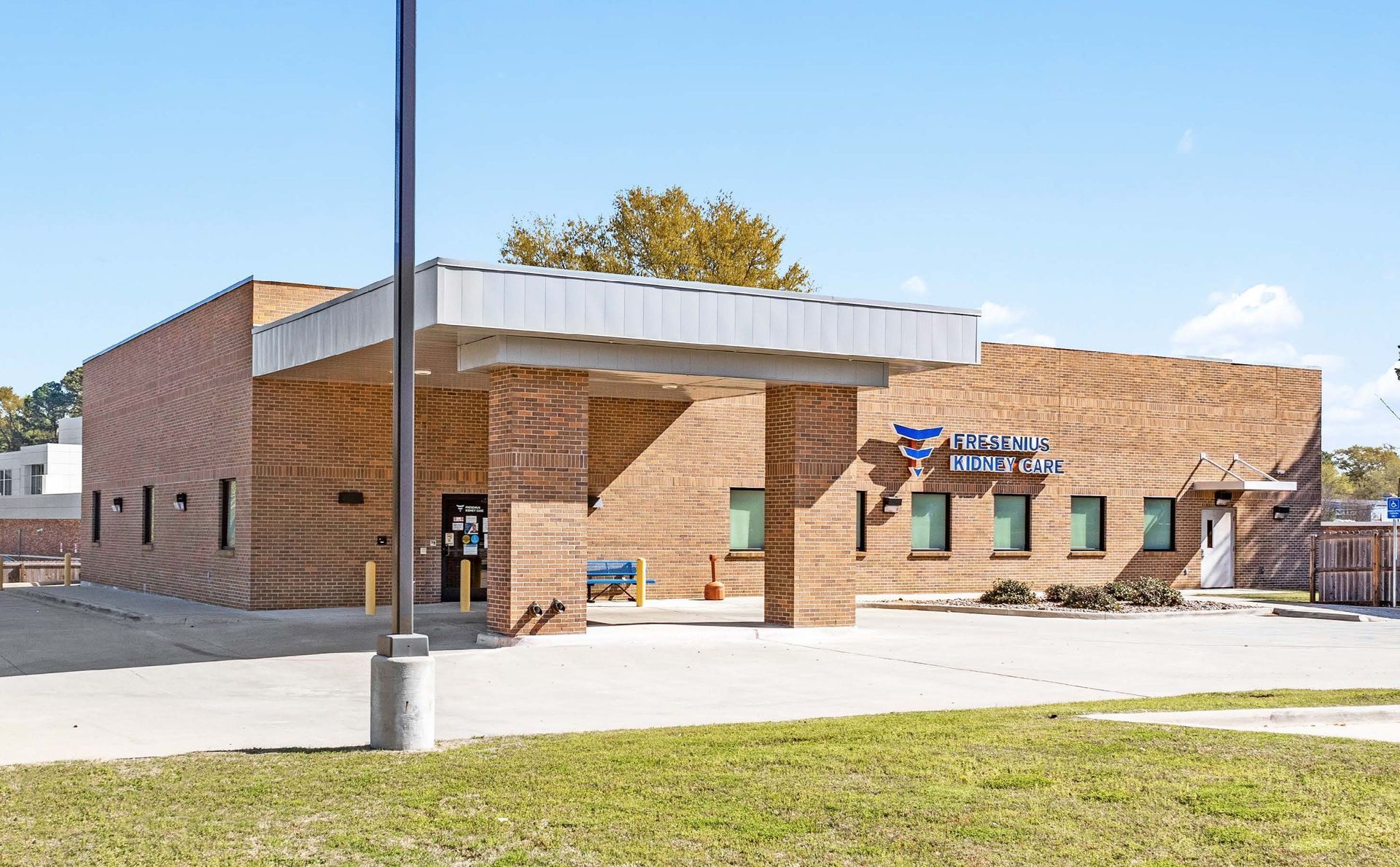 Fresenius Kidney Care building in Louisiana with a white awning, green-trimmed windows, and a sign by the entrance on a sunny day