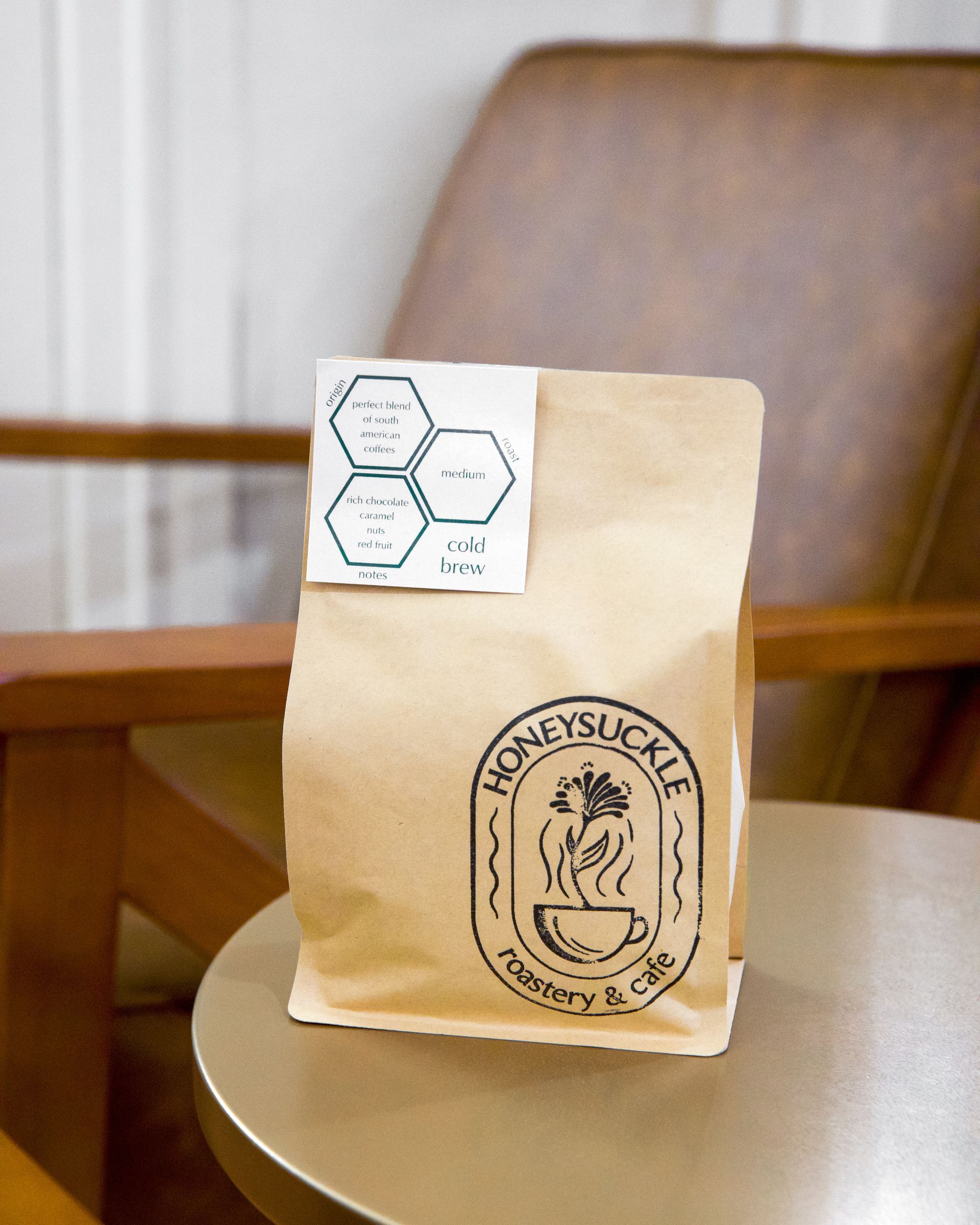 Brown paper bag with “Moneysuck” logo on a table, with a small white label at the top.