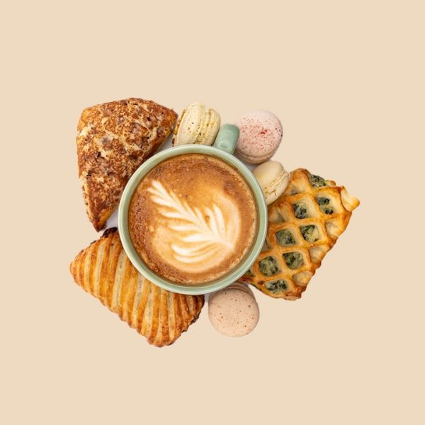 A cup of coffee is surrounded by pastries and macarons.