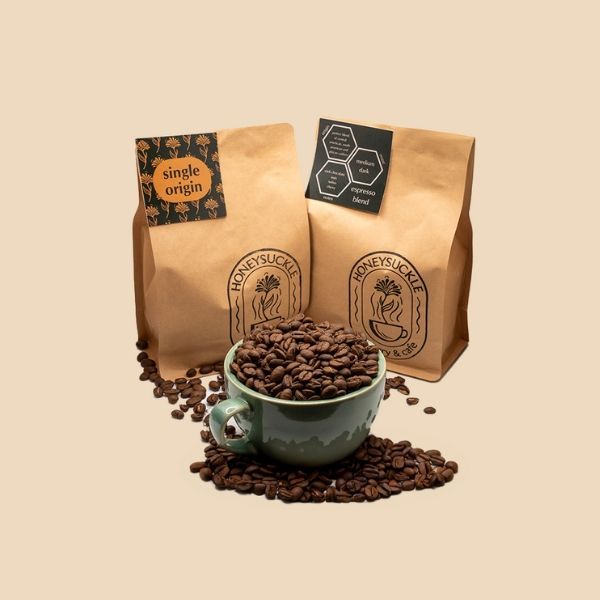 Three bags of coffee beans and a cup of coffee