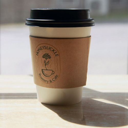 A honeysuckle coffee cup is sitting on a wooden table