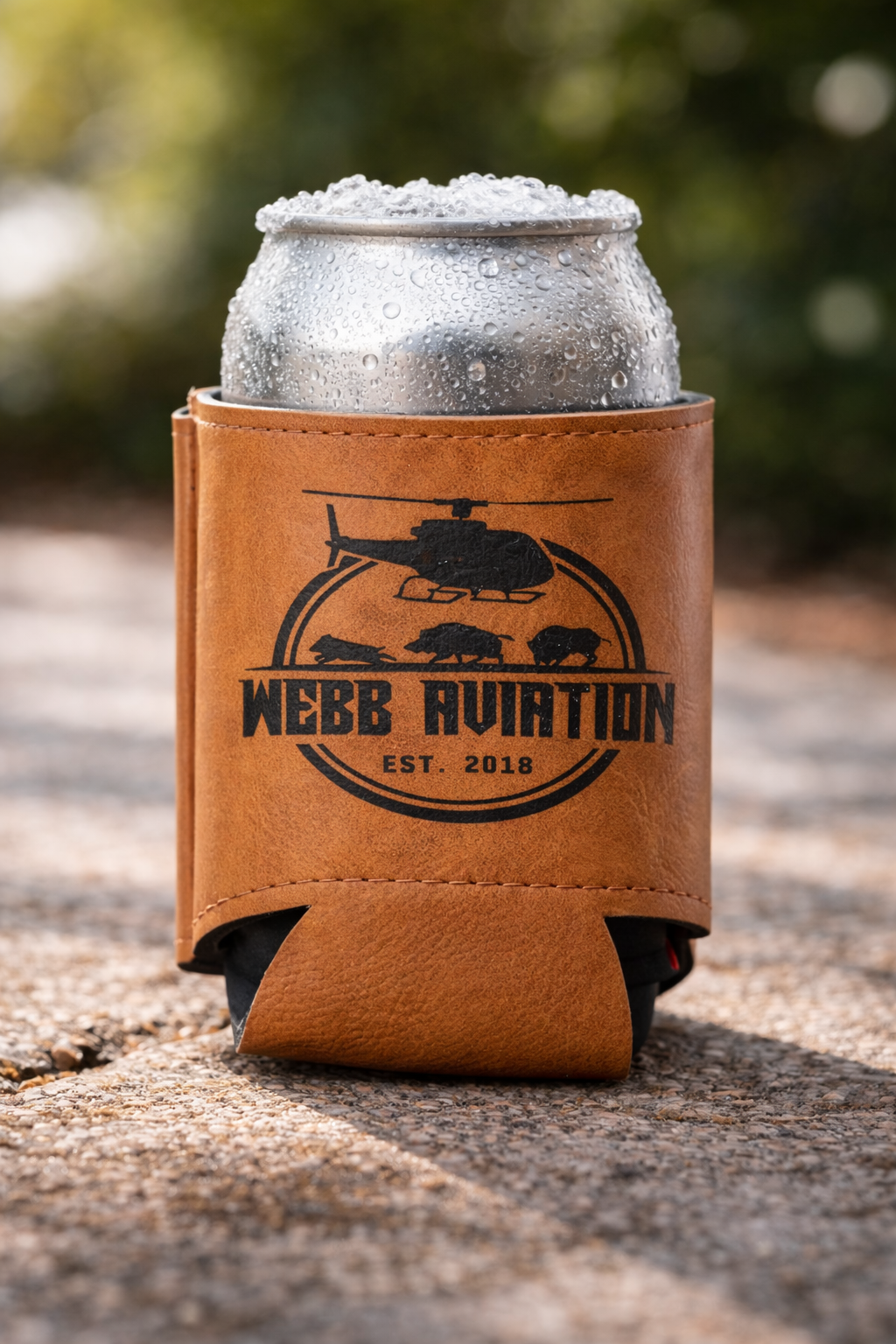 Tan leather beer koozie with black logo, standing on a white background