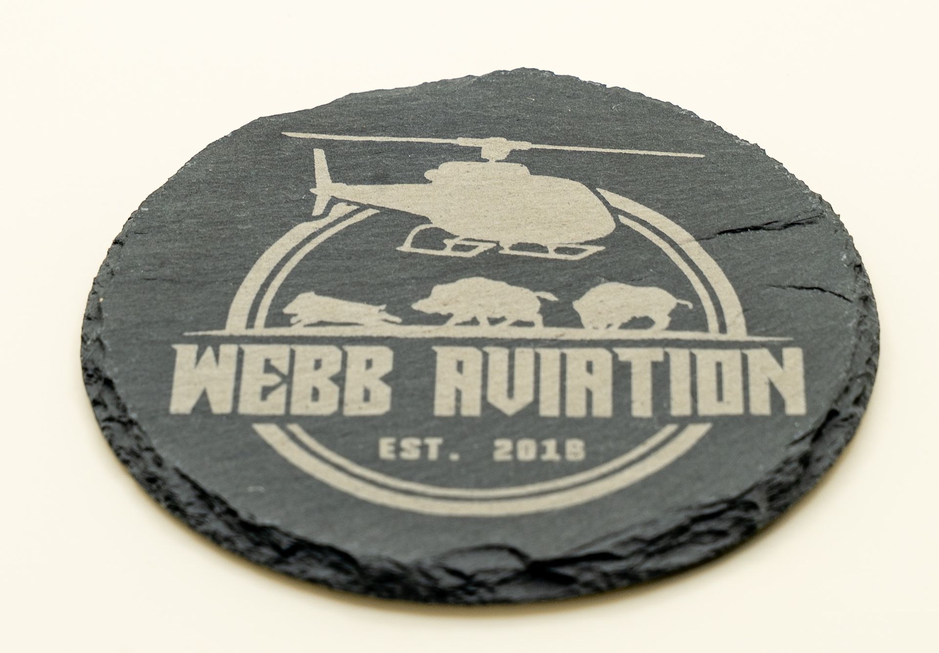 White “Webb Aviation” logo with helicopter and bear silhouettes on a gray stone tile.