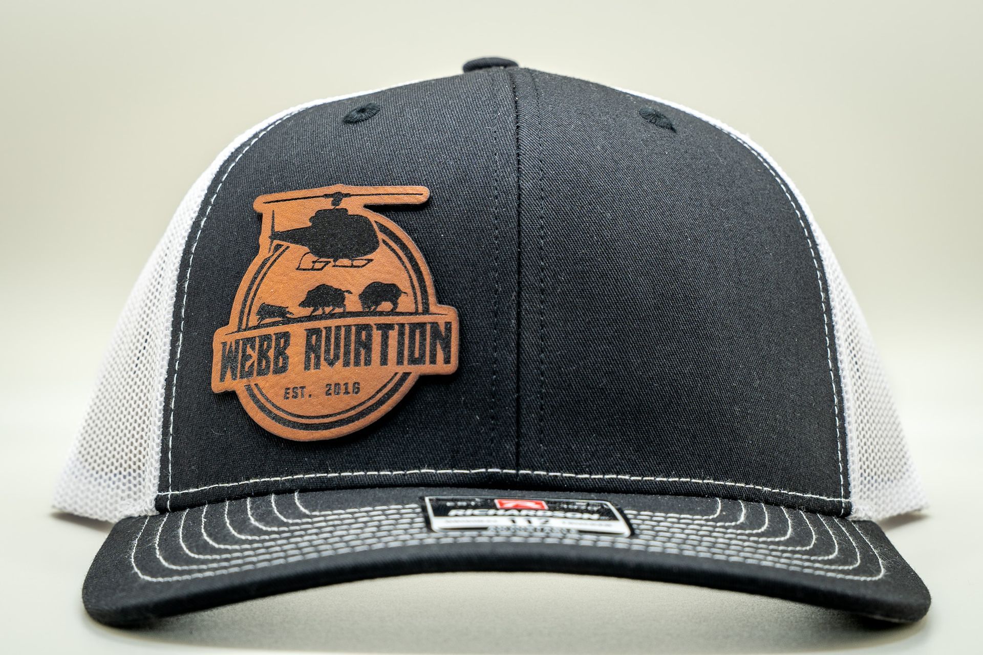 Black-and-white mesh trucker hat with orange logo patch reading “Bear Baution”