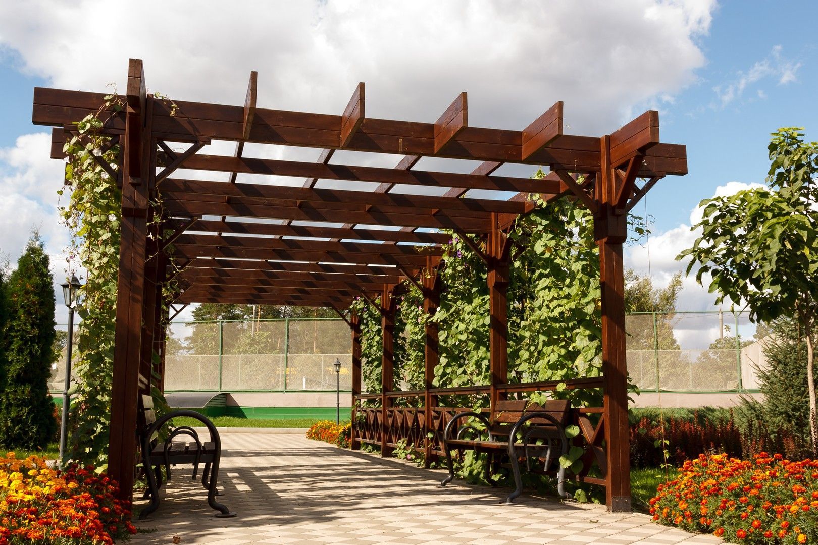 Un pergolato di legno con panchine sottostanti in un parco