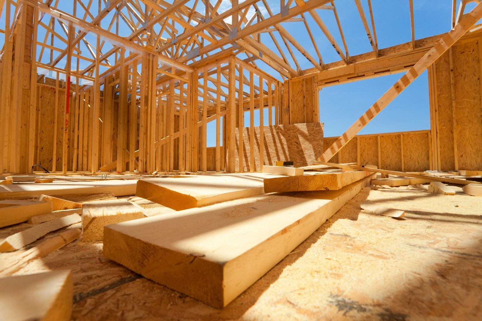 Si sta costruendo una casa con travi di legno e un cielo azzurro sullo sfondo.