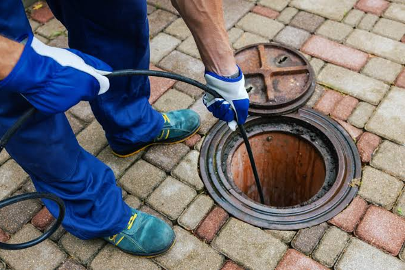 Technician servicing a commercial grease trap in a professional kitchen