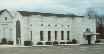 A white building with a black roof and a lot of windows