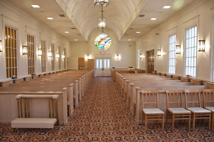 An empty church with rows of wooden benches and chairs