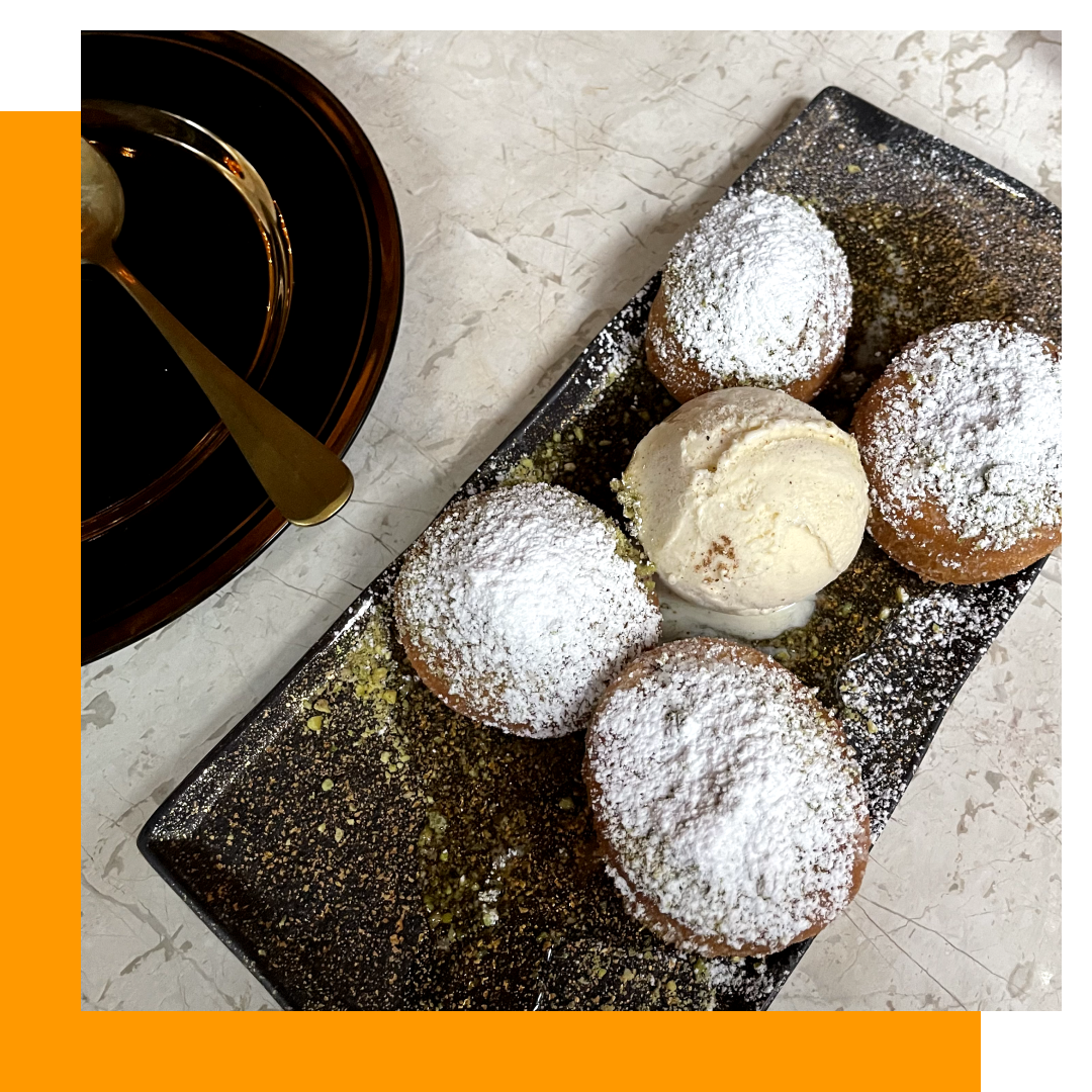 Five powdered donuts with ice cream, arranged on a rectangular serving dish.