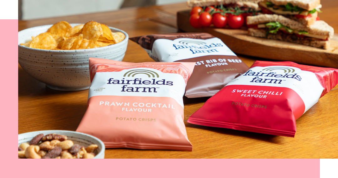Close-up of snacks: crisps, nuts, sandwiches, and three flavors of chips laid out on a table.