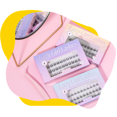 Pink makeup background with Lazy Girl Lashes boxes and a pink tweezer.