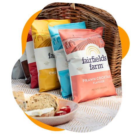 Bags of Fairfield Farm chips in a picnic basket. Includes sandwiches and cherries.
