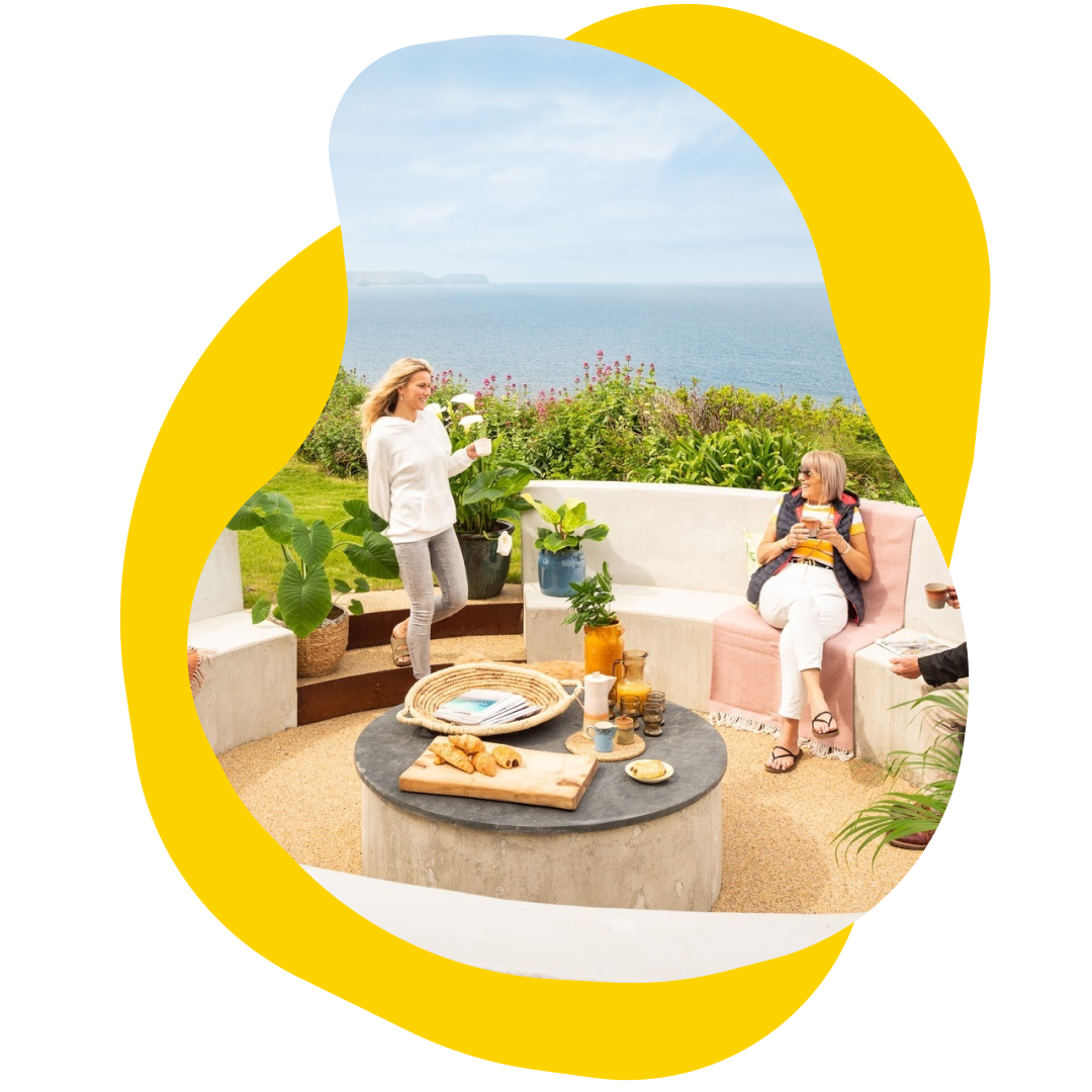 Two women enjoying drinks on a patio overlooking the ocean.