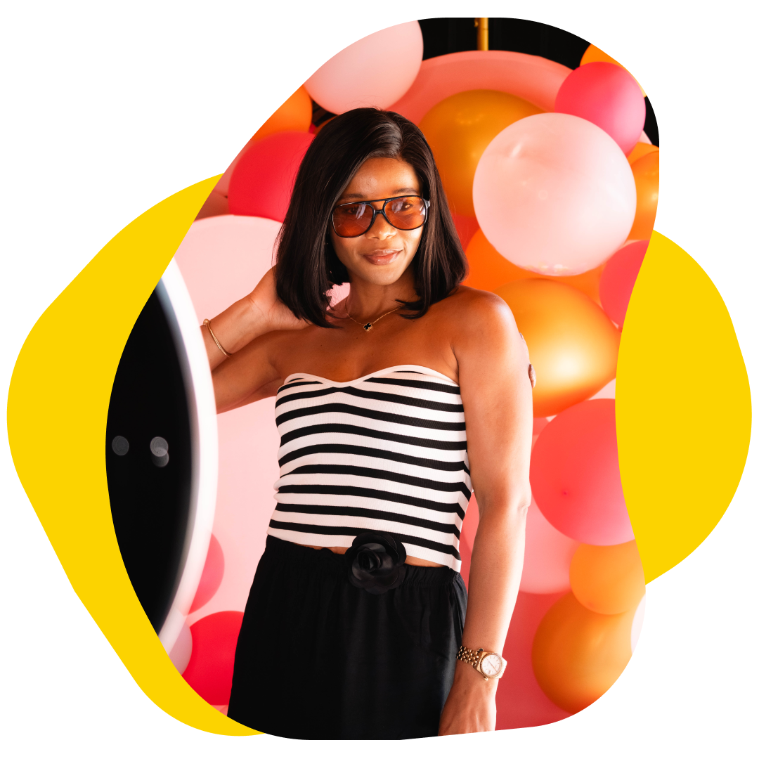 Woman in striped top and black skirt with sunglasses, posing in front of balloons.