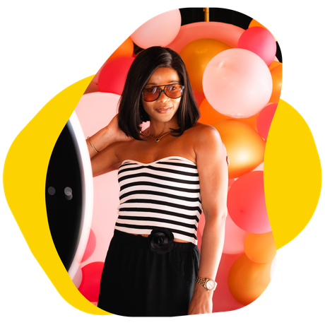 Woman in striped top and sunglasses, posing near balloons.